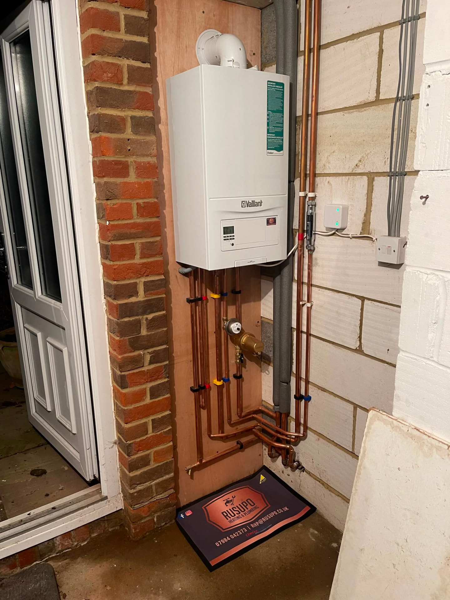 Wall-mounted Vaillant combi boiler installation with tidy copper pipework on a brick wall, fitted by Gas Safe registered engineers in Essex