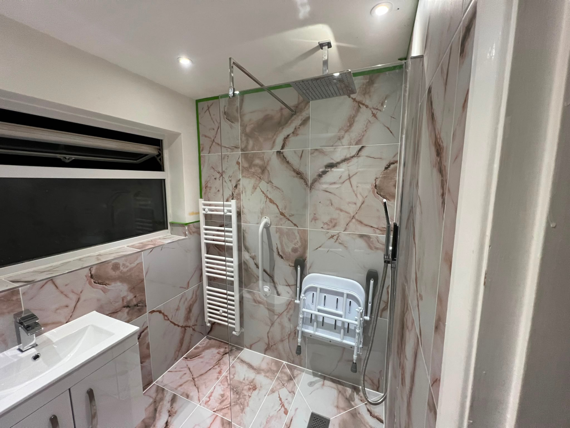Walk-in shower installation with rainfall shower head, grab rail and folding seat, fitted by Gas Safe registered engineers in Essex