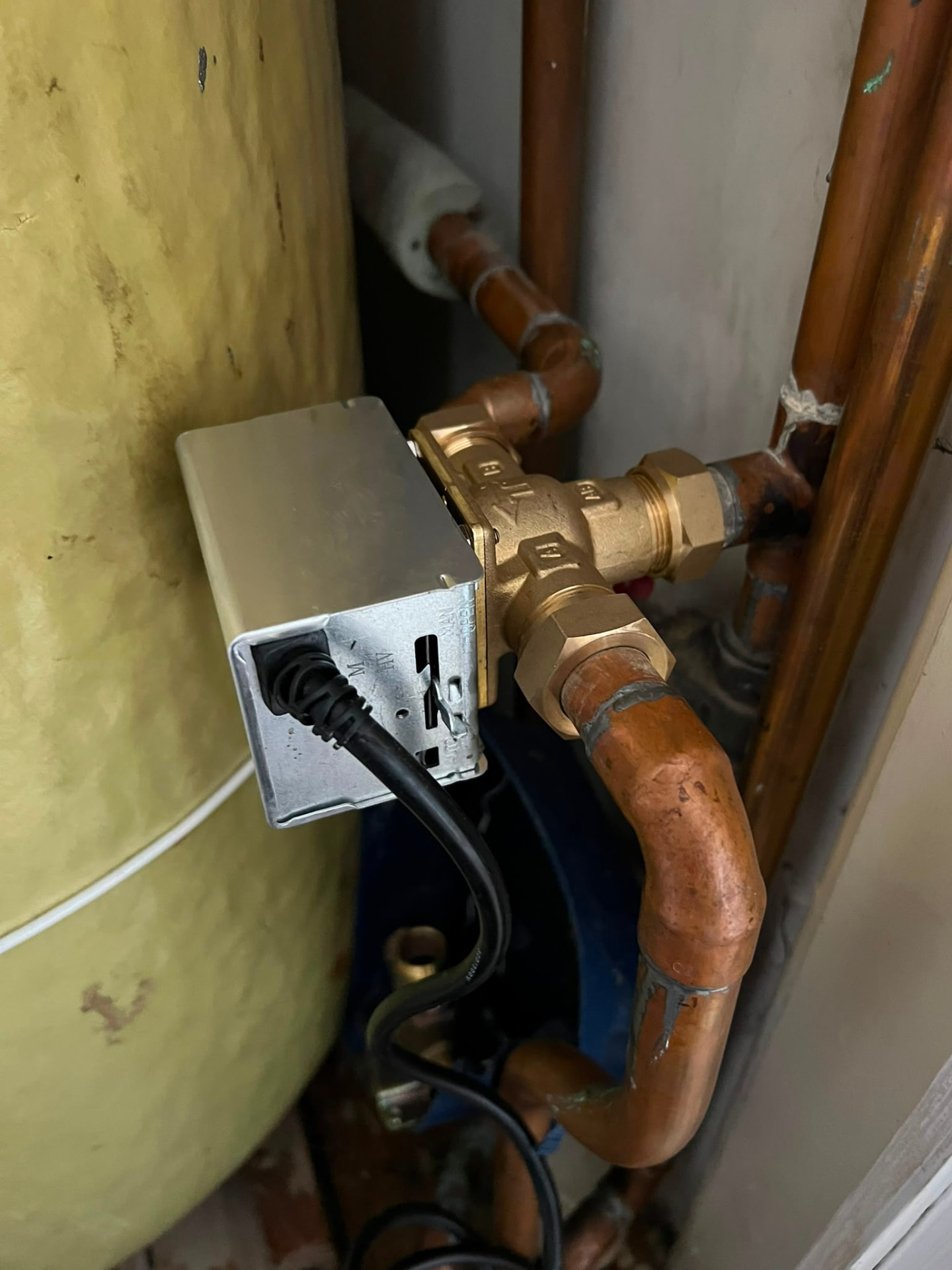 Motorised zone valve fitted to central heating pipework beside a hot water cylinder, fitted by Gas Safe registered engineers in Essex